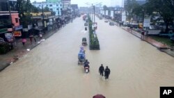 Warga menyeberangi jalanan yang tergenang banjir di Sylhet, Bangladesh, Minggu 18 Juni 2022. 