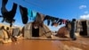 FILE - A woman hangs laundry in a flooded refugee camp in Idlib province, Syria, Dec. 21, 2021. 