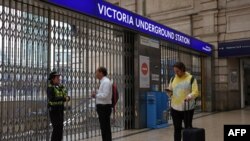 Seorang polisi berbicara dengan seorang komuter di pintu masuk stasiun kereta bawah tanah Victoria di London yang ditutup selama pemogokan 24 jam oleh hampir 4.000 staf stasiun Bawah Tanah London, 6 Juni 2022. (Foto oleh Hollie Adams / AFP)