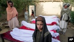 23일 아프가니스탄 파크티카주 거주민들이 지진 사망자 시신들 곁에 서 있다. 