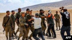 Sejumlah tentara Israel bentrok dengan warga Palestina dalam demo yang menentang penggusuran desa-desa warga Palestina di Hebron, Tepi Barat, pada 22 Juni 2022. Pihak Israel menggusur desa-desa tersebut untuk membuat zona latihan militer bagi tentaranya. (Foto: AFP/Mosab Shawer)