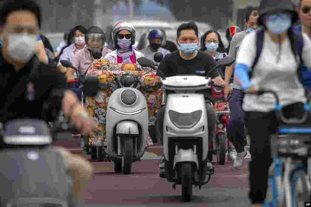 People wearing face masks ride across an intersection in the central business district in Beijing, China.