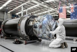 In this photo released by Rocket Lab, a technician works on a component of Rocket Lab's Electron rocket ahead of the launch on the Mahia peninsula in New Zealand on March 10, 2022. (Rocket Lab via AP)