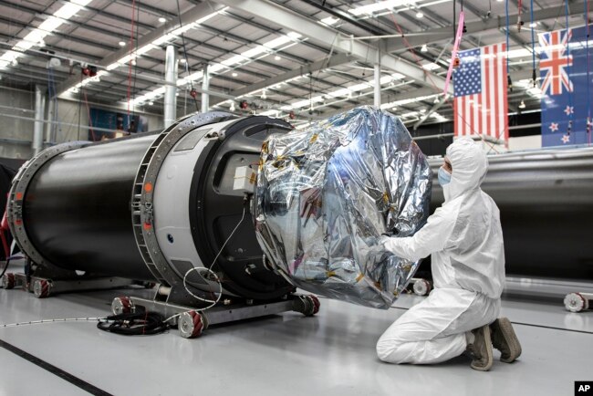 In this photo released by Rocket Lab, a technician works on a component of Rocket Lab's Electron rocket ahead of the launch on the Mahia peninsula in New Zealand on March 10, 2022. (Rocket Lab via AP)