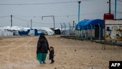 FILE - This file photo taken on March 4, 2021 shows a woman holds a child's hand at Camp Roj in Syria, where relatives of people suspected of belonging to the Islamic State (IS) group are held.