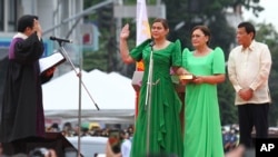 Sara Duterte, left, the daughter of outgoing populist president of the Philippines, takes her oath as vice president during rites in her hometown in Davao city, southern Philippines, June 19, 2022. 