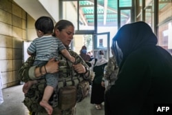 FILE - A medical officer assigned to the 82nd Airborne Division helps an Afghan woman and her child seeking to evacuate, at Hamid Karzai International Airport in Kabul, Aug. 25, 2021, in this handout photo courtesy of the U.S. Army.