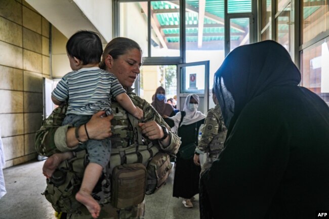 FILE - A medical officer assigned to the 82nd Airborne Division helps an Afghan woman and her child seeking to evacuate, at Hamid Karzai International Airport in Kabul, Aug. 25, 2021, in this handout photo courtesy of the U.S. Army.