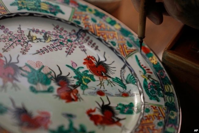 Joseph Tso, owner of Yuet Tung China Works, Hong Kong's last hand-painted porcelain factory, re-paints an old porcelain in Hong Kong, Wednesday, June 8, 2022. .(AP Photo/Kin Cheung)