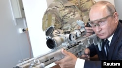 FILE PHOTO: Russian President Vladimir Putin aims a Chukavin sniper rifle SVCh-308 by Russian firearms maker Kalashnikov Concern at Patriot military theme park outside Moscow, Sept. 19, 2018.