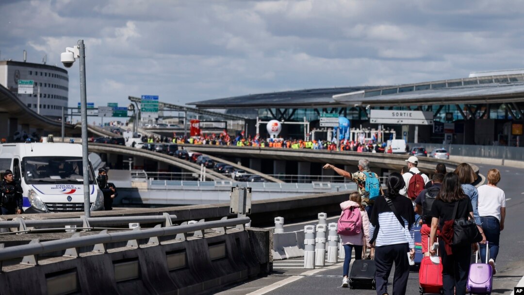 Wisatawan tiba dengan berjalan kaki di Bandara Roissy-Charles de Gaulle sementara pekerja bandara berdemonstrasi, Jumat, 1 Juli 2022 di bandara Roissy, utara Paris. (Foto: AP)