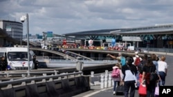 Wisatawan tiba dengan berjalan kaki di Bandara Roissy-Charles de Gaulle sementara pekerja bandara berdemonstrasi, Jumat, 1 Juli 2022 di bandara Roissy, utara Paris. (Foto: AP)