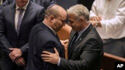 Israeli Prime Minister Naftali Bennett, left, and Foreign Minister Yair Lapid react after a vote on a bill to dissolve the parliament at the Knesset, Israel's parliament, in Jerusalem, June 30, 2022.