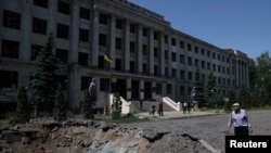 A passerby surveys a crater in the road caused by overnight shelling which damaged Kharkiv State Zoo Veterinary Academy, as Russia’s attack on Ukraine continues, in Mala Danylivka, Kharkiv Oblast, Ukraine, June 20, 2022.