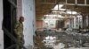 A Ukrainian serviceman looks at the ruins of the sports complex of the National Technical University in Kharkiv, Ukraine, June 24, 2022, damaged during a night shelling. 