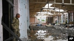 A Ukrainian serviceman looks at the ruins of the sports complex of the National Technical University in Kharkiv, Ukraine, June 24, 2022, damaged during a night shelling. 