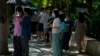 Residents stand in shade to avoid the sun's heat as they line up for coronavirus tests in Beijing, July 7, 2022. The Chinese capital is requiring people to show proof of COVID-19 vaccination before they can enter some public spaces.