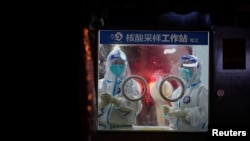 Medical workers in protective suits stand at a nucleic acid testing site in Shanghai, China, July 7, 2022. 