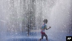 A child plays in a fountain in the warm weather in London, Friday, June 17, 2022. 
