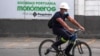 Un trabajador cpasa en bicicleta frente a un cartel de Monómeros Barranquilla, Colombia. [Archivo AFP]