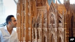 Fadel Alkhudr dari Suriah berpose di dekat bagian selatan model kayunya dari kata heritage Cologne Cathedral yang dipamerkan di Domforum di Cologne, Jerman, Senin, 20 Juni 2022. (Foto: AP)