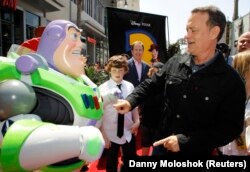 Aktor Tom Hanks (kanan) berinteraksi dengan karakter Buzz Lightyear (kiri) saat ia tiba di pemutaran perdana dunia "Toy Story 3" Disney Pixar di Teater El Capitan di Hollywood, California, 13 Juni 2010. (Foto: REUTERS/Danny Moloshok )