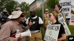 A clinic security officer, left, attempts to keep anti-abortion activist Doug Lane, left, from a physical confrontation with sign carrying abortion rights supporters, who are using noisemakers to drown out Lane's bullhorn outside the Jackson Women's Health Organization.