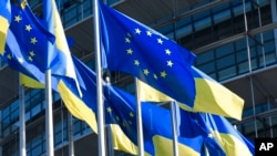 FILE - European and Ukraine flags fly outside the European Parliament, Tuesday, March 8, 2022 in Strasbourg, eastern France.