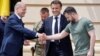 Ukrainian President Volodymyr Zelensky (R) shakes hands with Germany's Chancellor Olaf Scholz (L) next to France's President Emmanuel Macron prior to their meeting in Kyiv, on June 16, 2022.