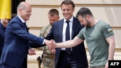 Ukrainian President Volodymyr Zelensky (R) shakes hands with Germany's Chancellor Olaf Scholz (L) next to France's President Emmanuel Macron prior to their meeting in Kyiv, on June 16, 2022.