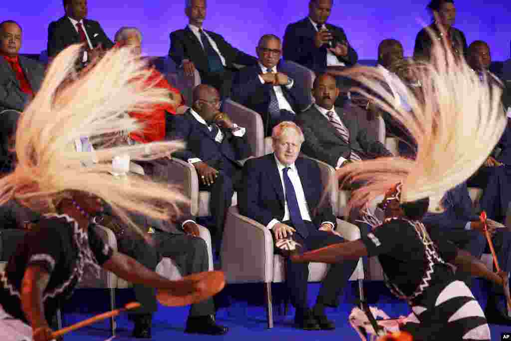 British Prime Minister Boris Johnson, center, looks at traditional dancers performing during the opening ceremony of the Commonwealth Heads of Government Meeting, in Kigali, Rwanda.