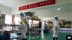 Health officials of the Pyongyang Sports Goods Factory disinfect the floor of a work place in Pyongyang, North Korea, June 14, 2022. The red banner says, 'Economy means increased production and patriotism.'