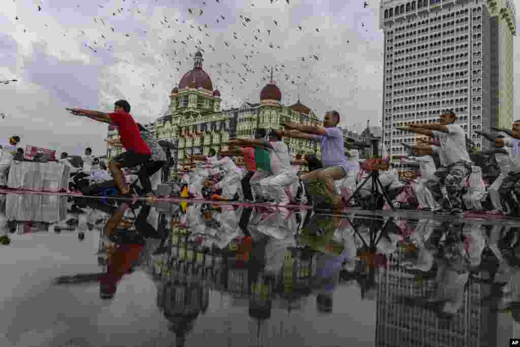 Orang-orang melakukan Yoga secara massal untuk memperingati Hari Yoga Internasional di depan hotel Taj Mahal Palace di kota Mumbai, India (21/6). (Foto: AP)