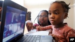 FILE — Lear Preston, 4, who attends Scott Joplin Elementary School, participates in her virtual classes as her mother, Brittany Preston, background, assists at their residence in Chicago's South Side, Feb. 10, 2021