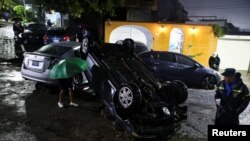 Personas observan vehículos dañados durante una inundación repentina causada por fuertes lluvias debido a la tormenta tropical Bonnie, en San Salvador, El Salvador, 2 de julio de 2022. REUTERS/José cabezas