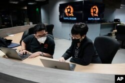 Lilibeth Frondoso (kanan), Rappler Multimedia Strategy and Growth Head, berbicara dengan seorang staf di dalam kantor mereka di kota Pasig, Filipina, Rabu, 29 Juni 2022. (AP/Aaron Favila)