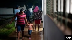 Una mujer y su hija caminan en un refugio temporal antes de la llegada de la tormenta tropical Bonnie en Bluefields, Nicaragua, el 1 de julio de 2022. (Foto de OSWALDO RIVAS / AFP)
