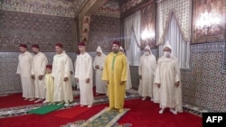 This image grab taken from footage provided by SNRT Maroc on July 10, 2022 shows King Mohammed VI praying on the first day of Eid al-Adha alongside his son, Crown Prince Moulay Hassan, and his brother, in the city of Sale. (Photo by SNRT Maroc / AFP) 