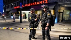 Security forces stand at the site where several people were injured during a shooting outside the London pub in central Oslo, Norway, June 25, 2022. 