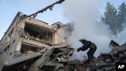 2022年7月4日，乌克兰哈尔科夫发生袭击事件后，一名救援人员正在清理被毁学校的瓦砾。（美联社）