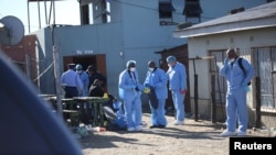 Equipa forense investiga após a morte de clientes encontrados dentro da Enyobeni Tavern, em Scenery Park, nos arredores de East London, na província de Eastern Cape, África do Sul, em 26 de Junho de 2022.