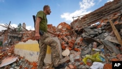 A Ukrainian serviceman looks at the rubble of a school that was destroyed some days ago during a missile strike in outskirts of Kharkiv, Ukraine, July, 5, 2022. 