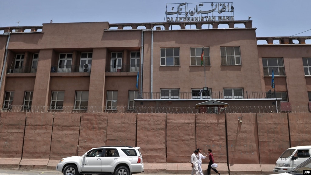 FILE - Afghan men walk past Da Afghanistan Bank, Afghanistan's central bank, in Kabul on June 28, 2011. 