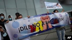 Manifestantes que denuncian violaciones de derechos humanos contra sus familiares sostienen un cartel que dice en español "¡Di no a la tortura!" frente a la sede del a oficina para el desarrollo, de la ONU, en Caracas, Venezuela, el 29 de octubre de 2021.