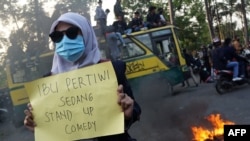 Seorang siswa memegang poster 'Ibu Pertiwi Sedang Stand Up Comedy' pada hari kedua aksi unjuk rasa menentang UU Omnibus Penciptaan Lapangan Kerja, di Tangerang, 7 Oktober 2020. ( FAJRIN RAHARJO / AFP)