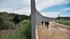 FILE - Police officers patrol along a steel fence along the Evros river, Greece's river border with Turkey, near the village of Poros, June 8, 2021. 