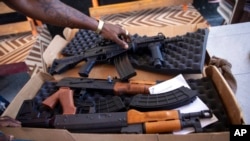 FILE - A G9 gang coalition member unpacks weapons in Port-au-Prince, Haiti, Oct. 6, 2021. 