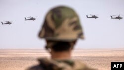 Un membre des Forces armées royales marocaines observe le survol des hélicoptères d'attaque AH-64 Apache de l'armée américaine lors du deuxième exercice militaire annuel "African Lion" dans la région de Tan-Tan, dans le sud-ouest du Maroc, le 30 juin 2022