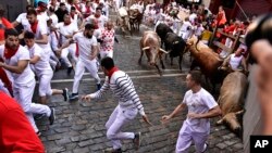 Gente corriendo por la calle con toros bravos y cabestros, en el primer día de encierros en las Fiestas de San Fermín en Pamplona, en el norte de España, el martes 7 de julio de 2022. (AP Foto/Álvaro Barrientos)