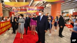In this photo released by Xinhua News Agency, Chinese President Xi Jinping, center and his wife Peng Liyuan, center left, wave to welcoming crowd as they arrive at a train station in Hong Kong, June 30, 2022. 